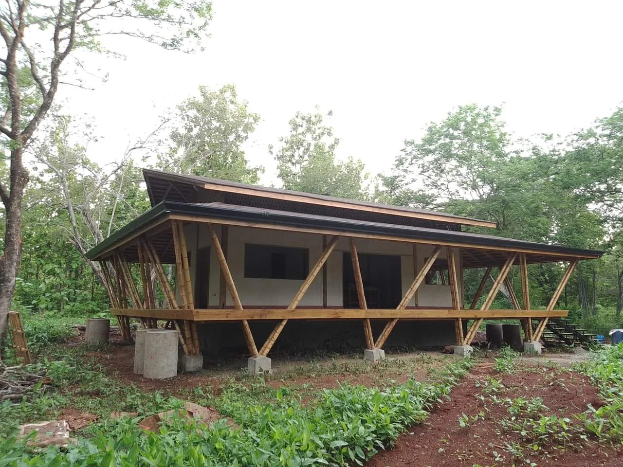 Casa de madera de Serrano Prado con terraza abierta y estructura artesanal, rodeada de naturaleza