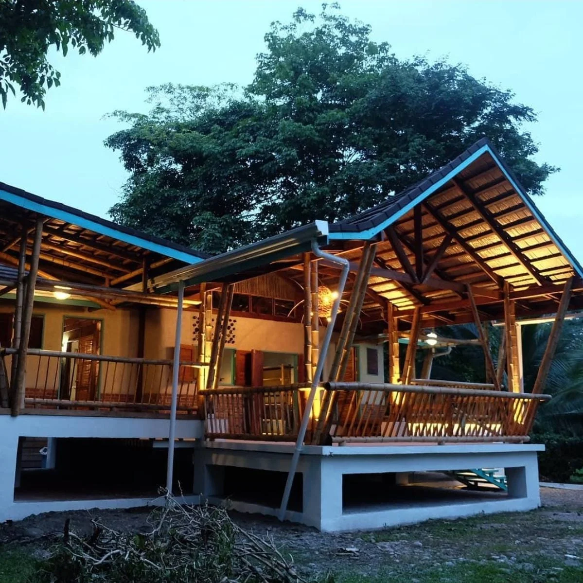 Cabaña de madera construida por Serrano Prado, iluminada al atardecer entre árboles